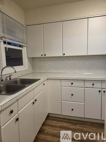 A kitchen with white cabinets and a sink.