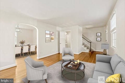 A living room with a grey couch, a grey armchair, a coffee table, and a dining table with chairs.