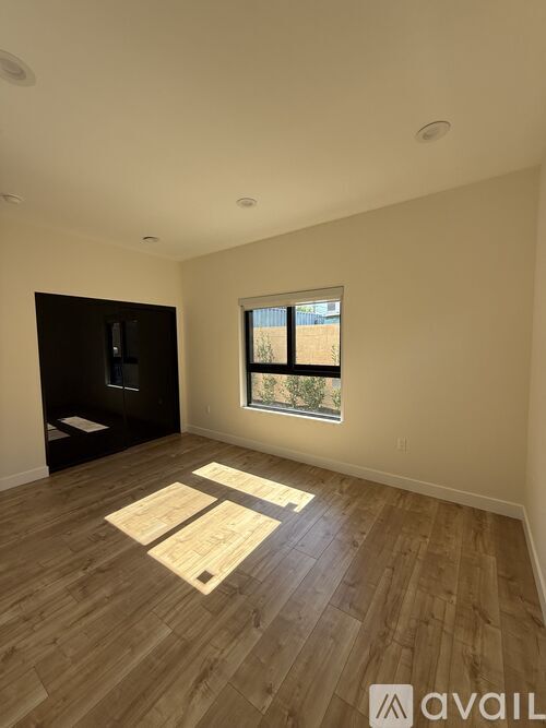 A room with wooden flooring and a window showing a view of a building outside.