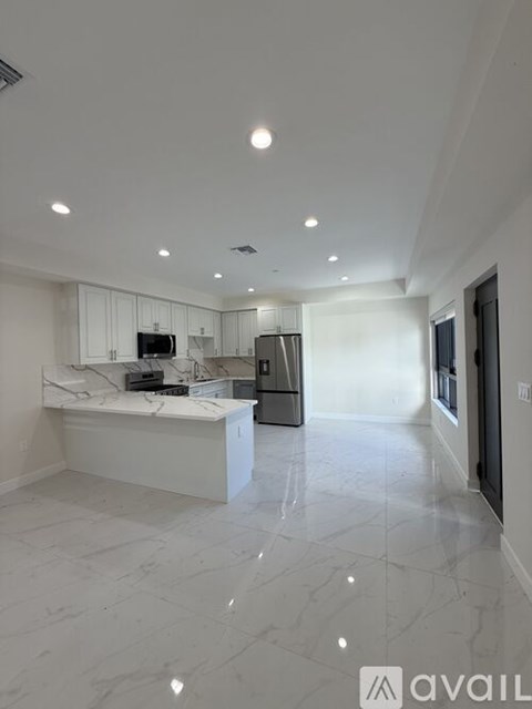 A modern kitchen with white cabinets and a marble countertop.