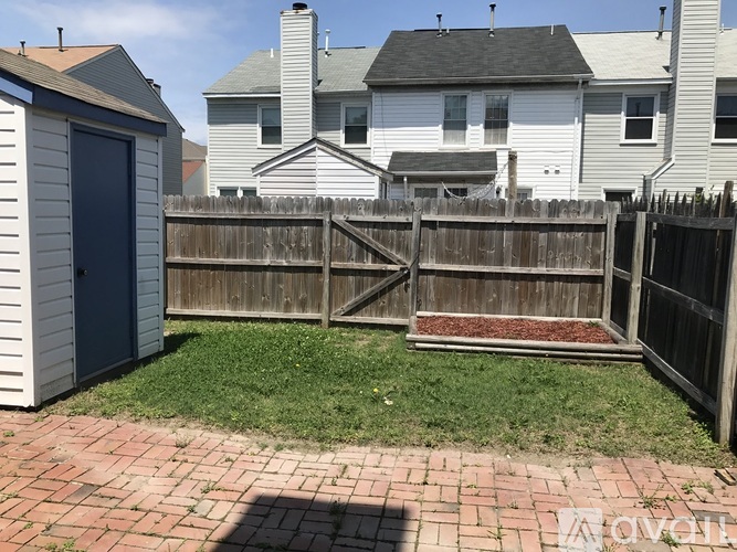 A backyard with a wooden fence and a brick walkway.