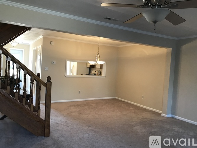 A spacious room with a ceiling fan and a staircase leading to the upper floor.