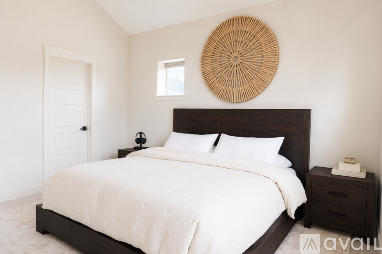 A bedroom with a large bed and a round woven wall hanging.