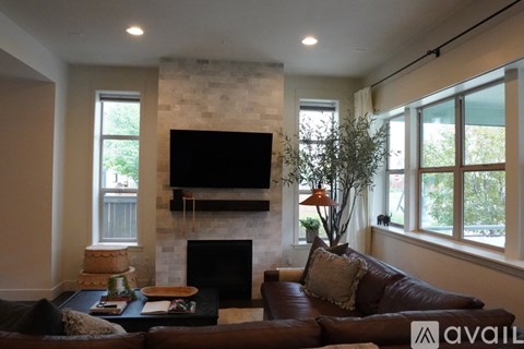 A living room with a brown leather couch and a flat screen TV mounted above a fireplace.
