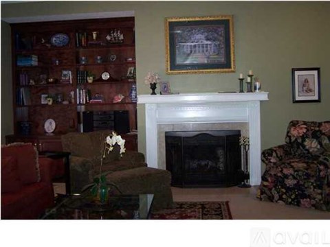 A living room with a fireplace, a chair, a sofa, a coffee table, and a painting on the wall.