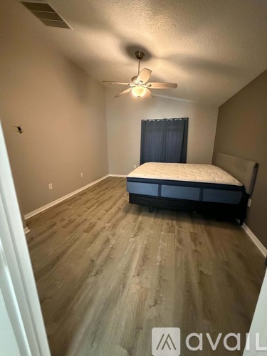 A bedroom with a bed, ceiling fan, and wooden flooring.