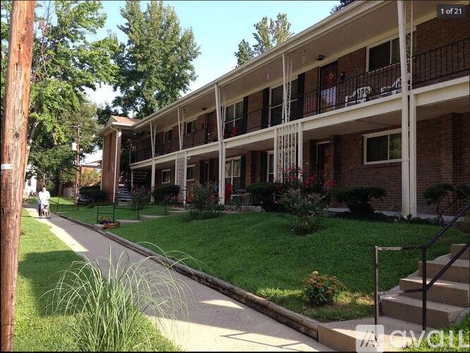 A street view of apartment buildings with green lawns and trees.