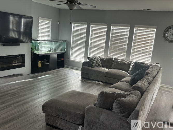 A living room with a grey couch and a fireplace.