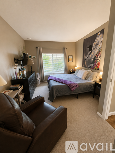 A bedroom with a bed, a couch, and a painting on the wall.