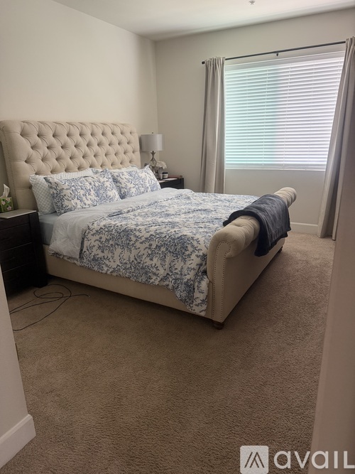 A bedroom with a large bed and a window with blinds.