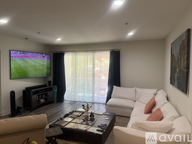 A living room with a television on the wall and a couch with a pillow on it.