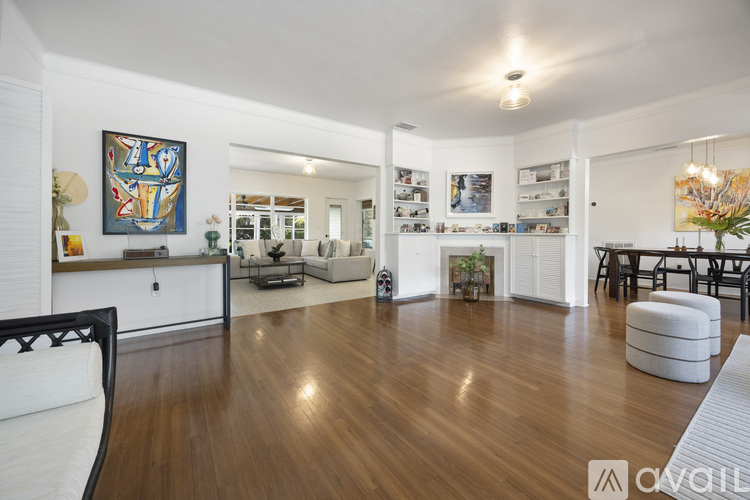 A living room with a white couch and a painting on the wall.