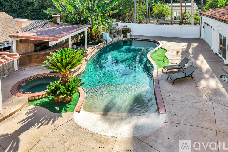 A pool with a small waterfall and a palm tree.