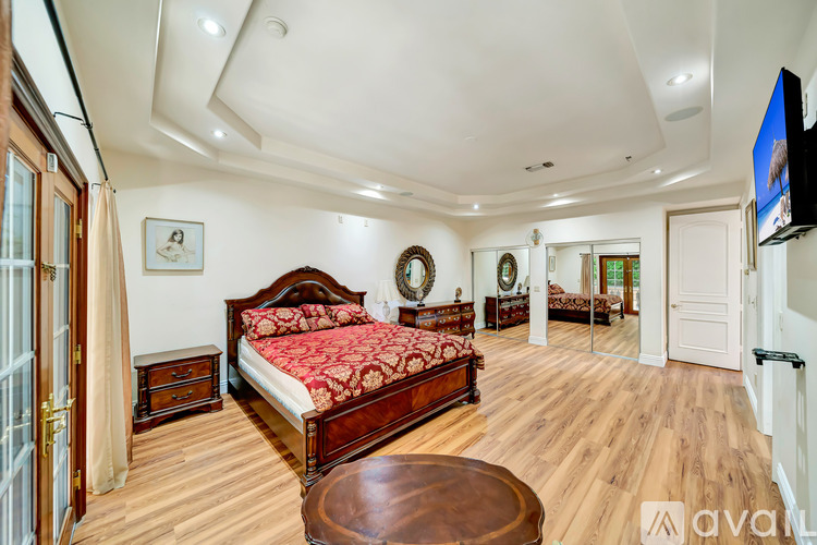 A bedroom with a large bed and a wooden floor.