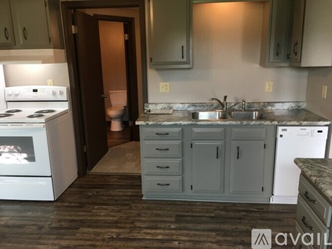 A kitchen with a white stove and a sink with a dishwasher.