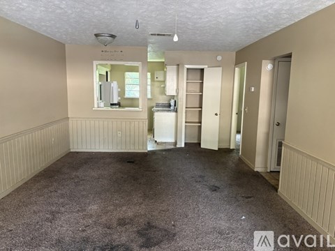 A room with beige walls and a carpeted floor is available for rent.