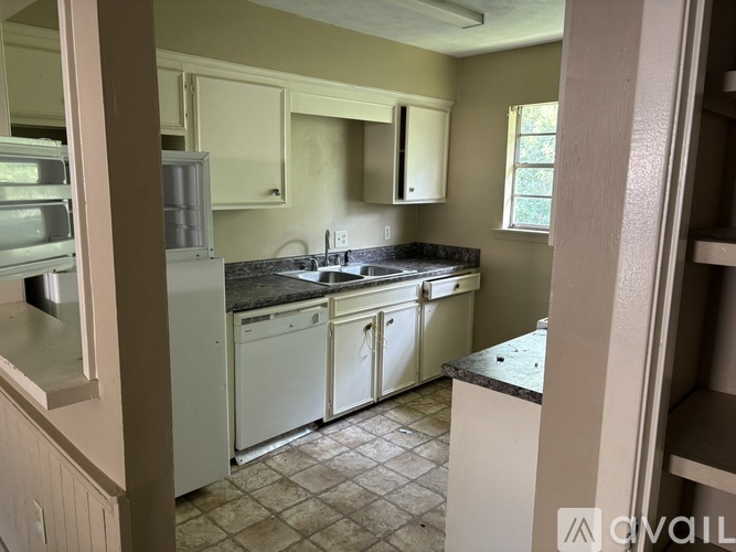A kitchen with white appliances and a black countertop.