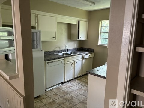 A kitchen with white appliances and a black countertop.