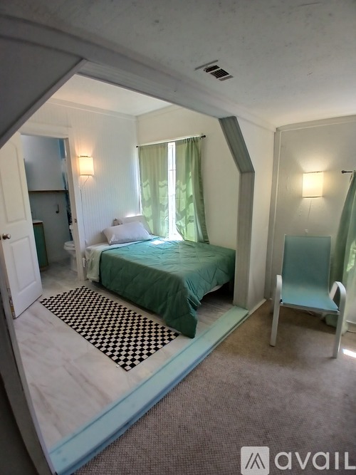 A bedroom with a bed, chair, and mirror.