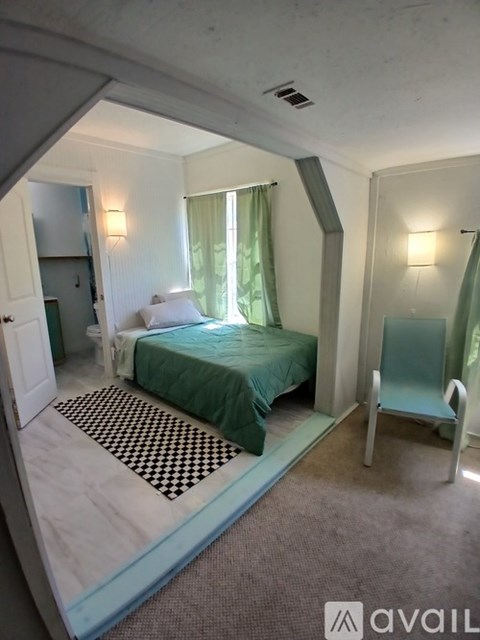 A bedroom with a bed, chair, and mirror.