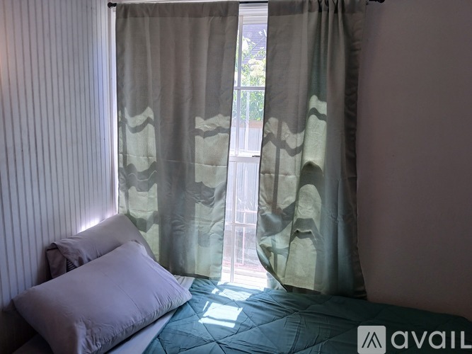 A bedroom with a bed and a window with curtains.