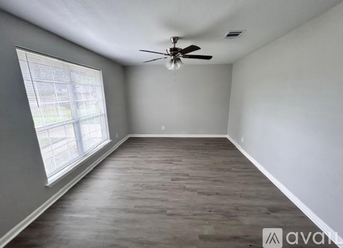 A room with a ceiling fan and a window with blinds.