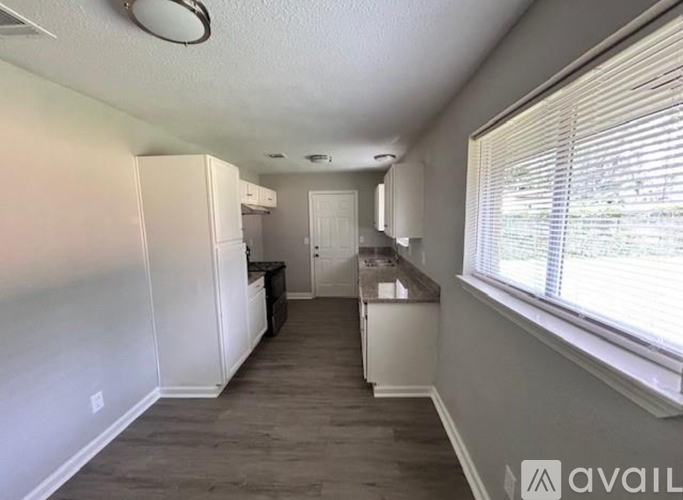 A kitchen area with white cabinets and a black fridge.