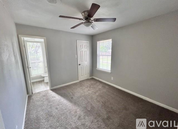 A room with a ceiling fan and two windows.