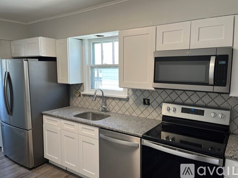 A kitchen with a refrigerator, microwave, oven, and sink.