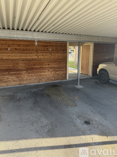 A white car is parked in front of a wooden garage door.