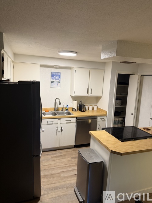 A kitchen with a black refrigerator and white cabinets.