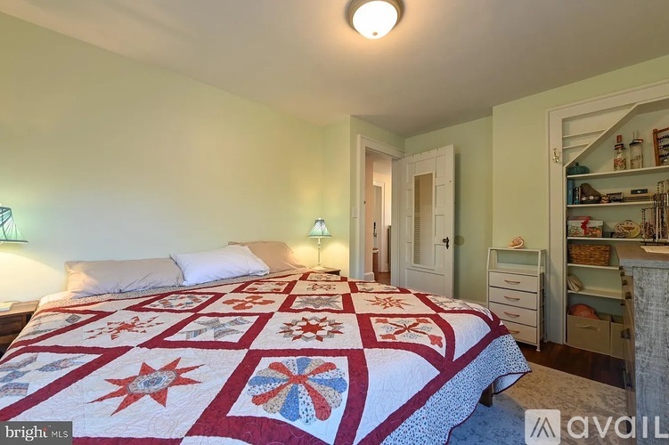 A bedroom with a bed, dresser, and a quilt on the bed.