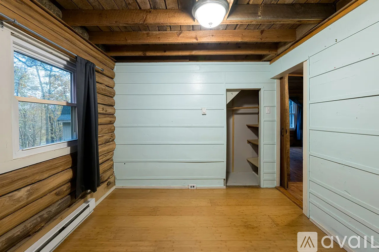 A room with wooden walls and a window with a view of trees.