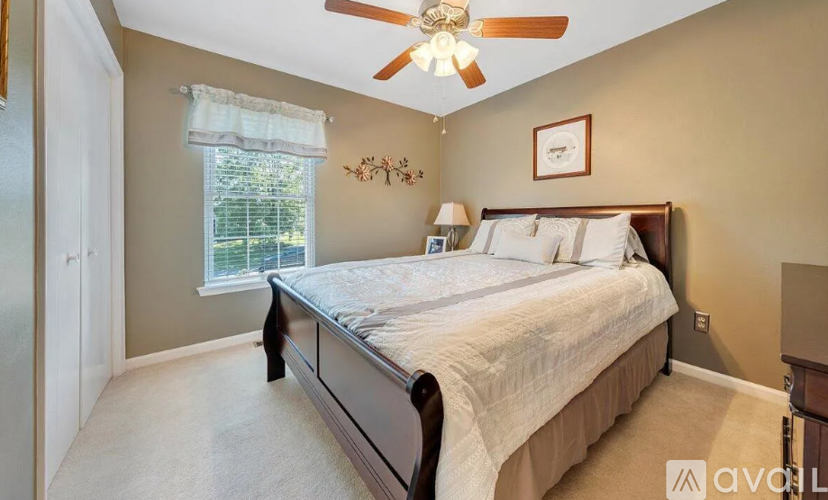 A bedroom with a bed, a ceiling fan, and a window with blinds.