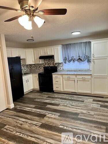 A kitchen with black appliances and white cabinets.