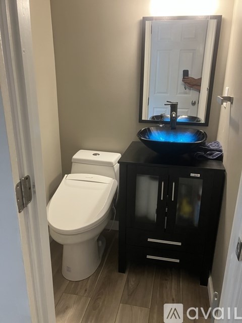 A bathroom with a toilet, sink and cabinet.