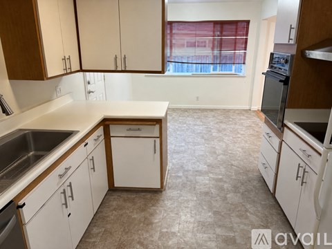 A kitchen with white cabinets and a tiled floor.