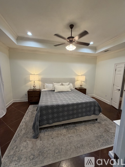 A bedroom with a bed, two lamps, and a ceiling fan.