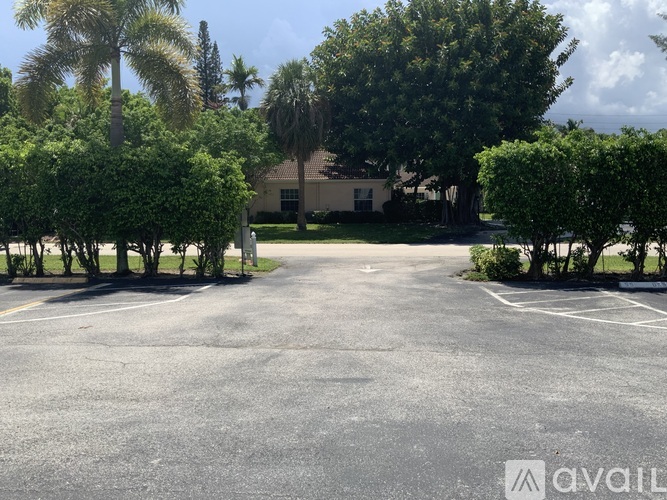 A parking lot with a building and trees in the background.