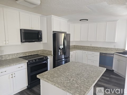 A kitchen with white cabinets and a granite countertop.