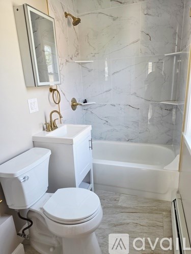 A white toilet sits next to a white sink in a marble bathroom.