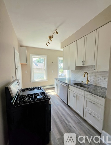 A kitchen with a black stove top oven and white cabinets.