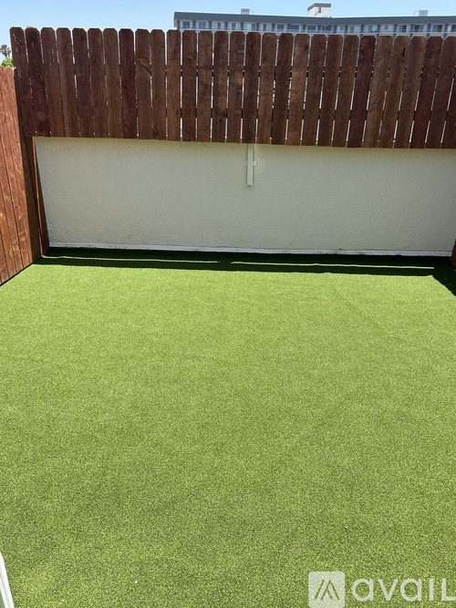 A backyard with a white fence and artificial grass.