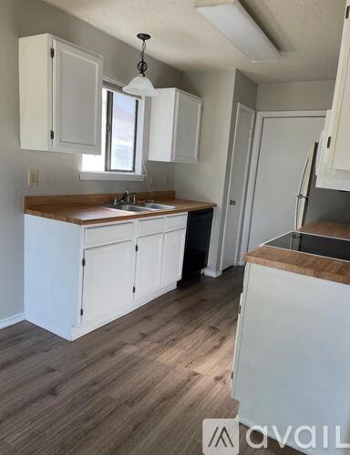A kitchen with white cabinets and a wooden countertop.