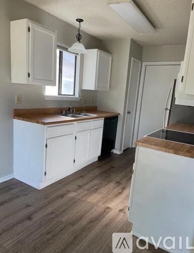 A kitchen with white cabinets and a wooden countertop.