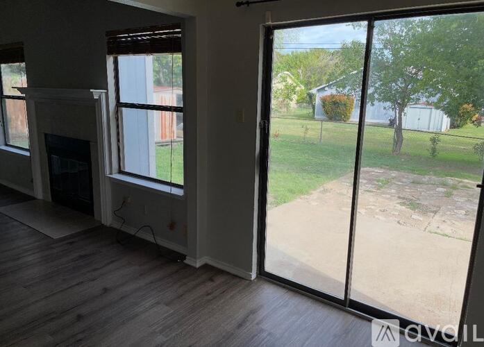 A room with a fireplace and sliding glass doors that open to a backyard.