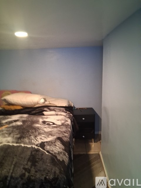 A bed with a wolf print is in a room with a white wall.