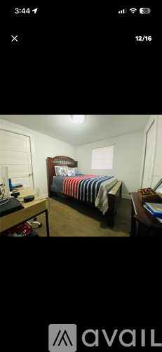 A bedroom with a bed, desk, and chair.