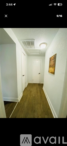 A long hallway with wood floors and white walls.