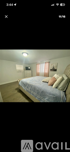 A bedroom with a bed, nightstand, and window with curtains.